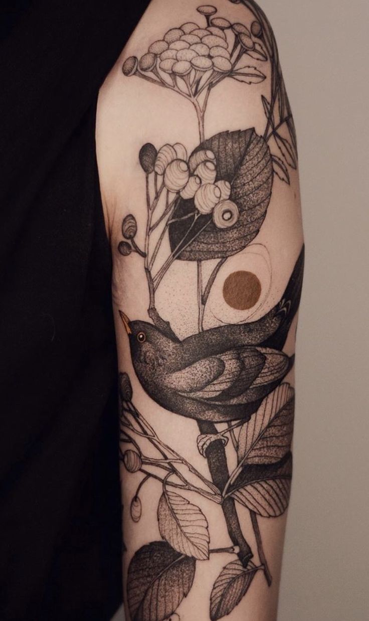 a woman's arm with a bird and flowers on it