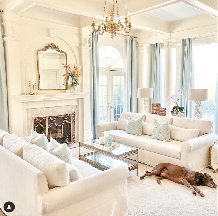 a living room filled with furniture and a fire place under a chandelier in front of a fireplace