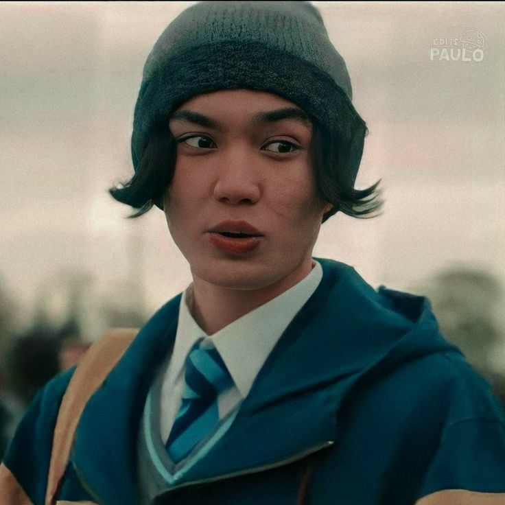 a young man wearing a blue tie and a green hat with his eyes wide open