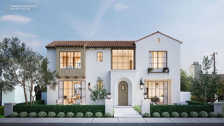 a white two story house with lots of windows and bushes in front of the house