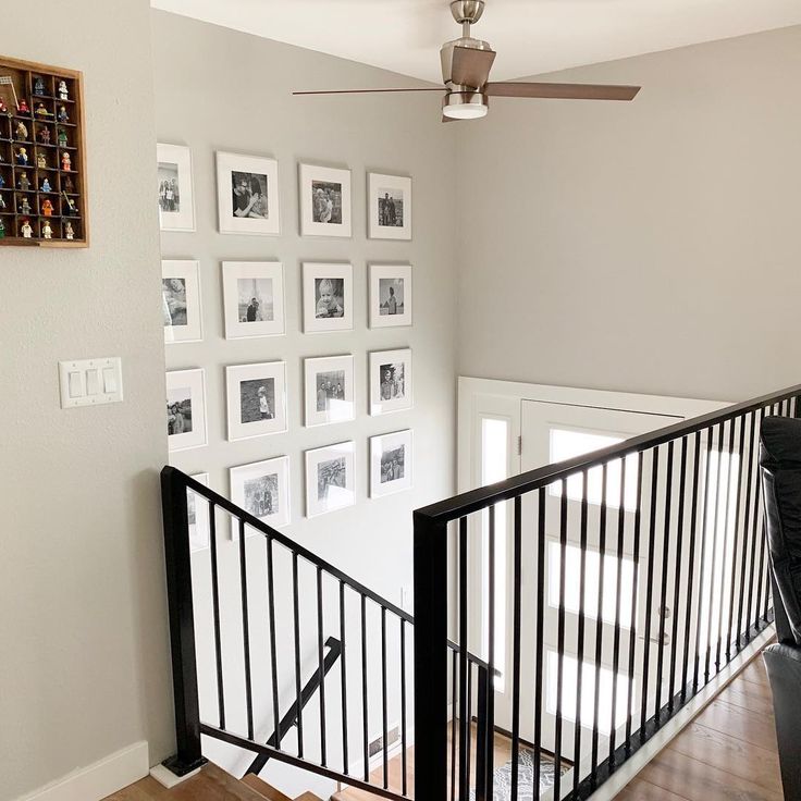 there is a staircase with pictures on the wall and a ceiling fan in front of it