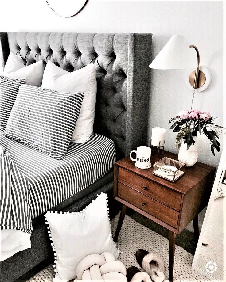 a bedroom with black and white bedding, striped comforter, pillows and a nightstand