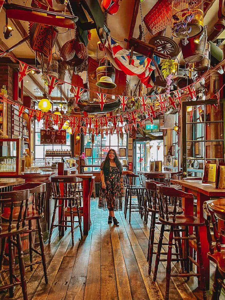 a woman standing in the middle of a room filled with lots of wooden tables and chairs