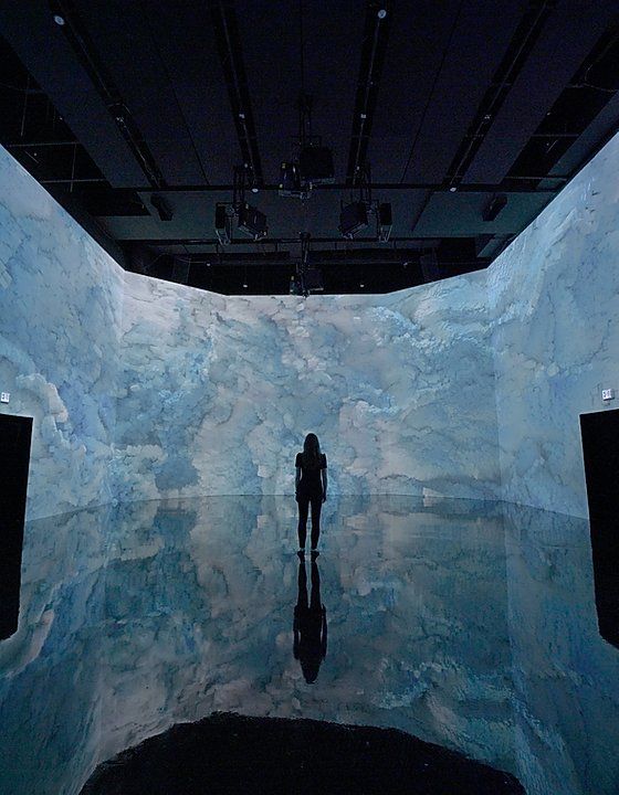 a person standing in front of an ice wall with water and clouds on the walls