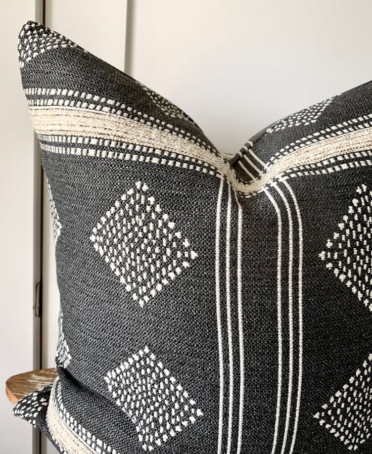 a black and white pillow sitting on top of a wooden table