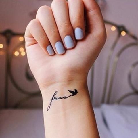 a woman's hand with a small tattoo on her wrist that says faith and an arrow