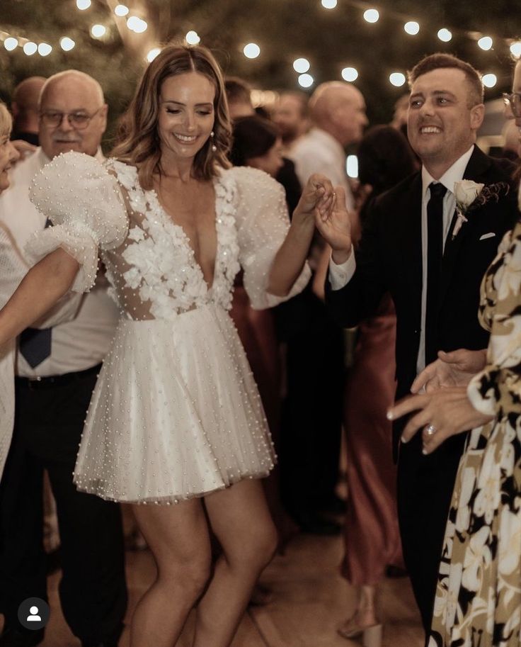 a woman in a short white dress dancing with other people