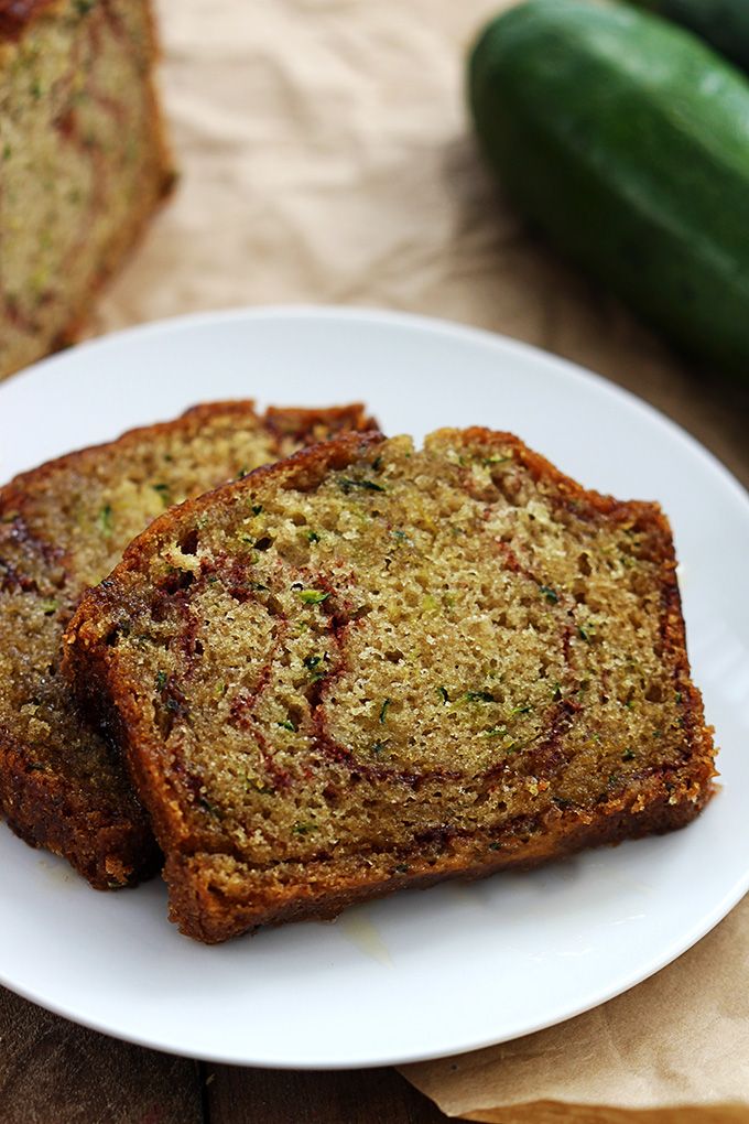 three slices of zucchini bread on a white plate next to another piece of bread