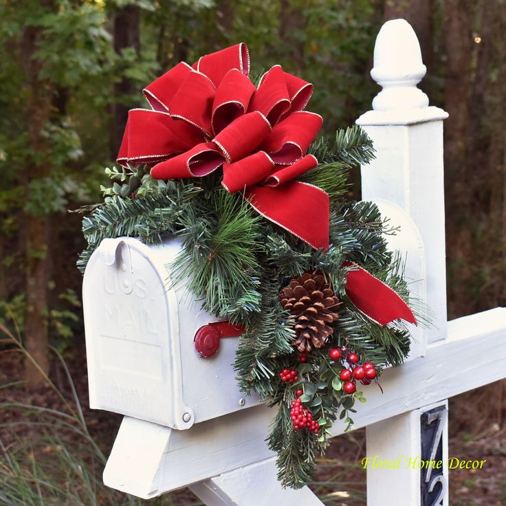 a white mailbox decorated with red bows and pine cones