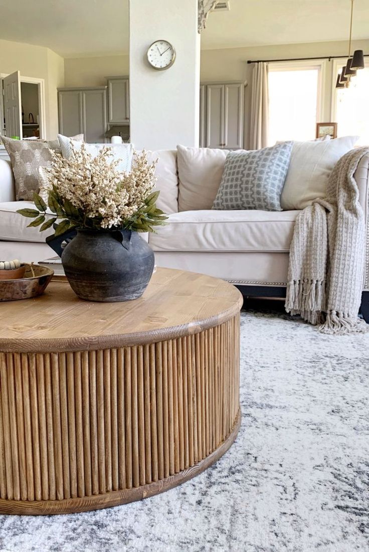 a living room filled with furniture and a large vase on top of a coffee table