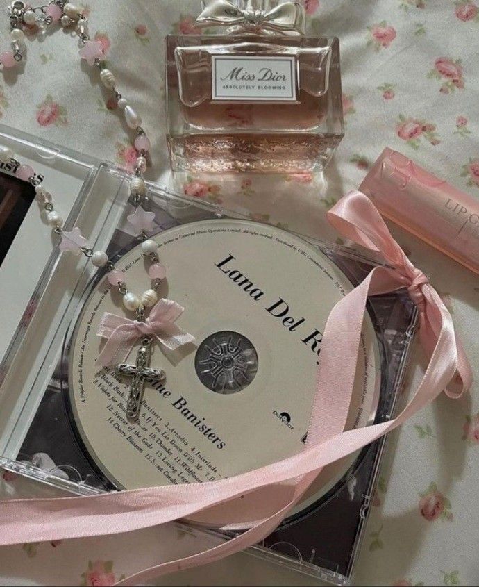 the contents of a perfume bottle, cd and necklace laid out on a bed