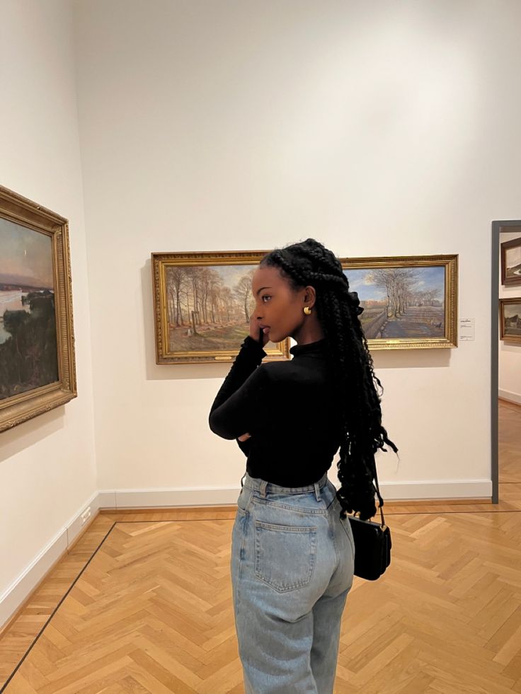 a woman standing in an art gallery talking on her cell phone