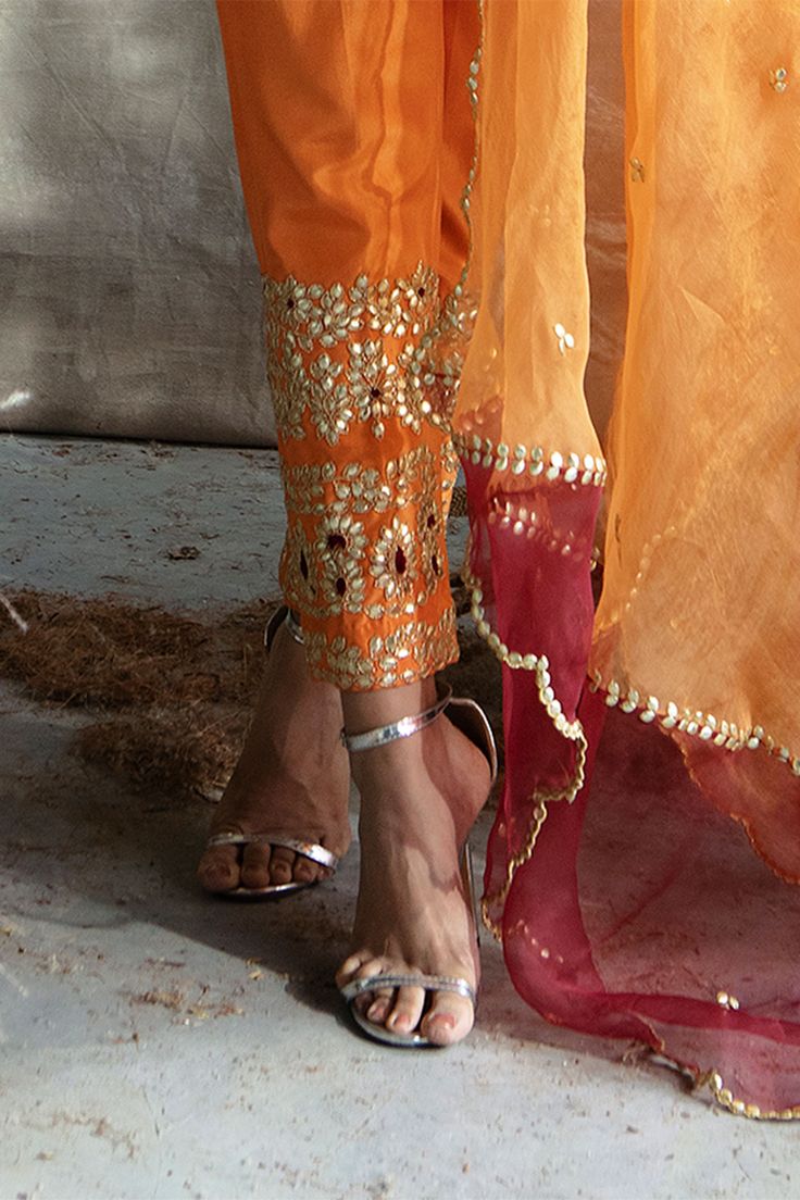 Orange short kurta with all-over embroidered motifs and round neck. Paired cigar pants and dupatta.
Component: 3
Embroidered
Neckline: Leaf
Sleeve Length: Full
Fabric: Silk, Organza
Color: Orange
French knots, beads and gota embroidery
Flared short kurta
Drawstring at the waist with latkans
Embroidered dupatta - Aza Fashions Traditional Pants With Embroidered Border For Festivals, Diwali Churidar With Embroidered Border, Unstitched Bollywood Festive Bottoms, Chanderi Sets With Embroidered Border For Navratri, Traditional Embroidered Bottoms For Diwali, Festive Pants With Zari Work And Traditional Drape, Traditional Pants With Embroidered Border For Eid, Fitted Pants With Zari Work For Festivals, Fitted Bollywood Pants With Zari Work