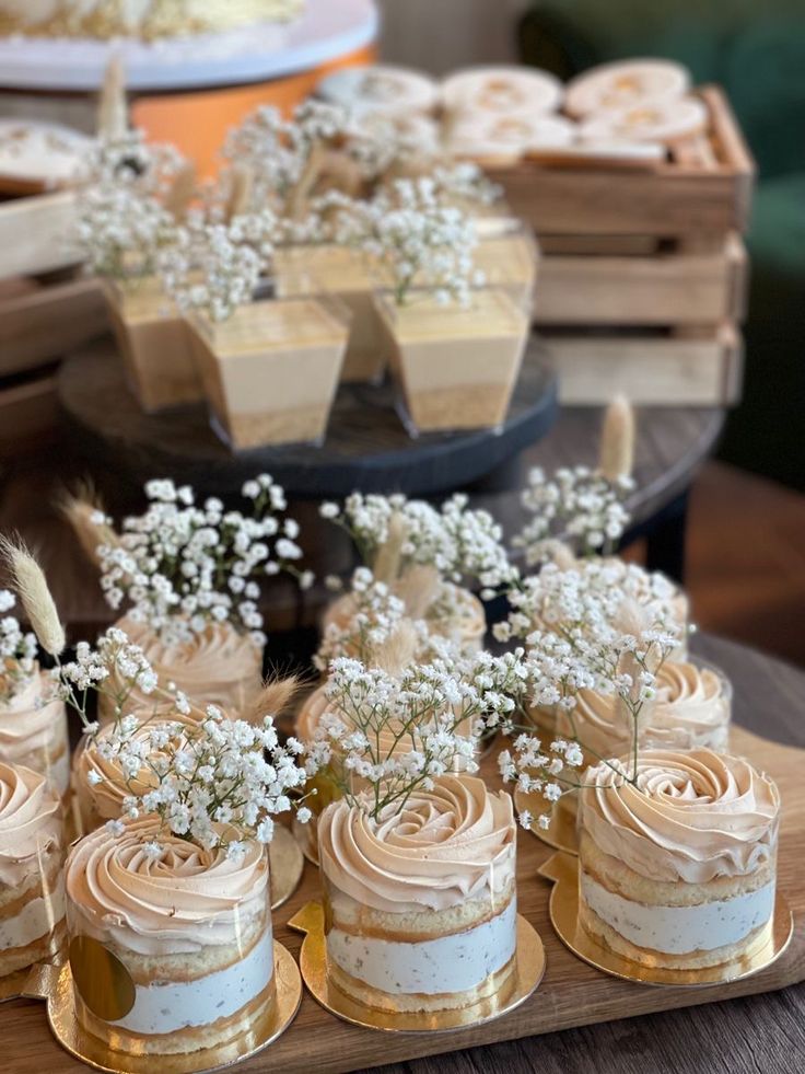 there are many small cakes and cupcakes on the table with flowers in them