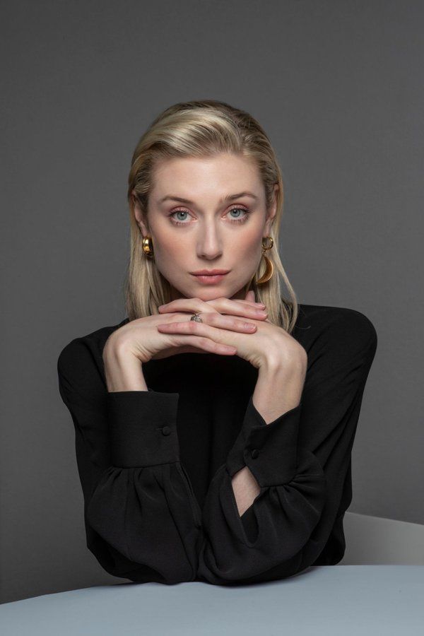 a woman sitting at a table with her hands on her chin and looking off to the side