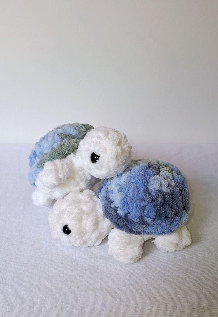 three small stuffed animals sitting next to each other on a white tablecloth covered surface