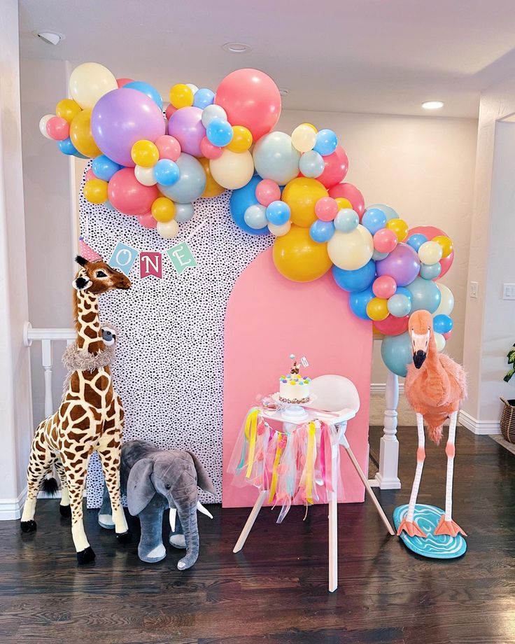 two giraffes are standing in front of a birthday arch with balloons on it