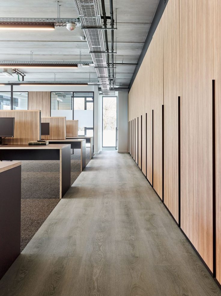 an empty office with wood paneling and open cubicles on either side of the room