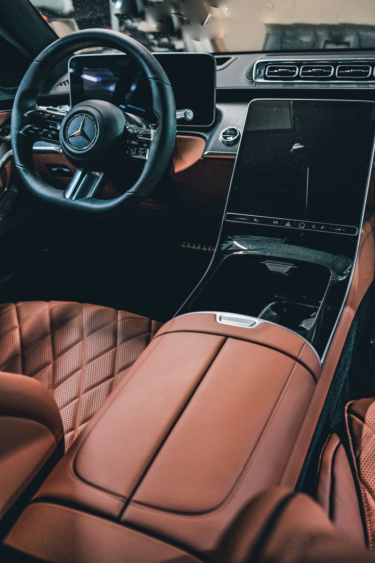 the interior of a car with brown leather seats and steering wheel, including an electronic display