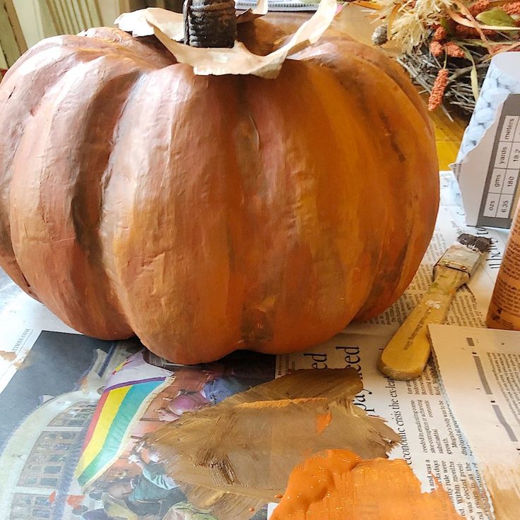 a large pumpkin sitting on top of a table next to a banana peel and newspaper