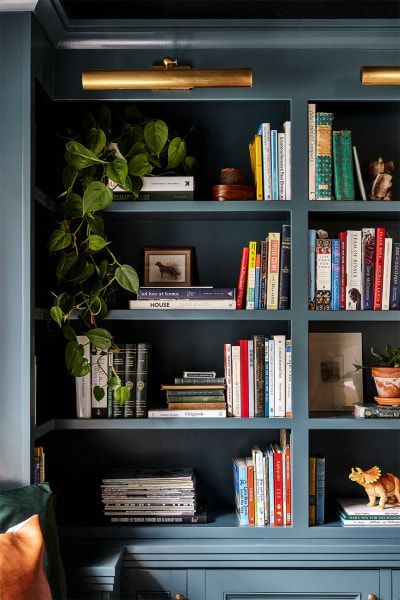 a bookshelf filled with lots of books next to a plant