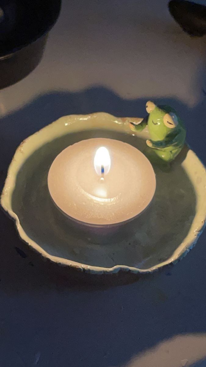 a lit candle sitting in a bowl on top of water