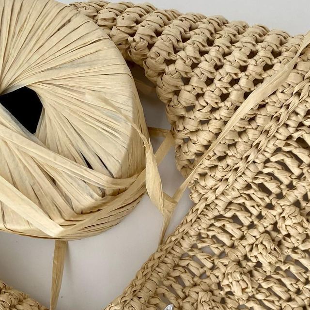 a piece of woven material sitting on top of a white table next to a bag