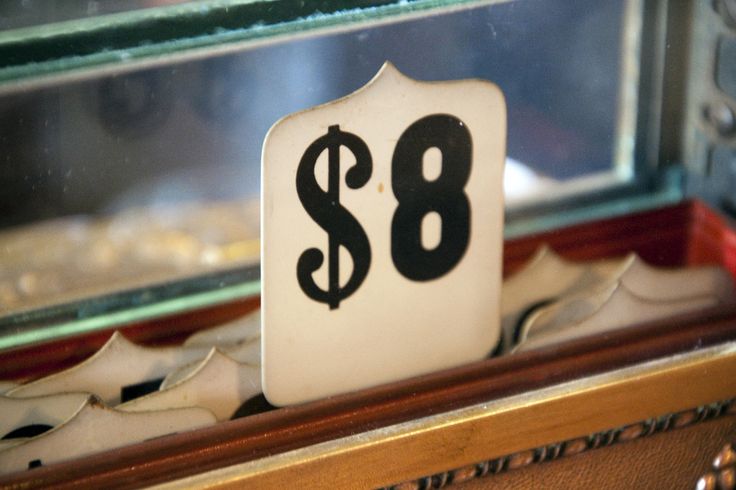 a sign that says $ 8 on it in front of a glass case filled with shoes