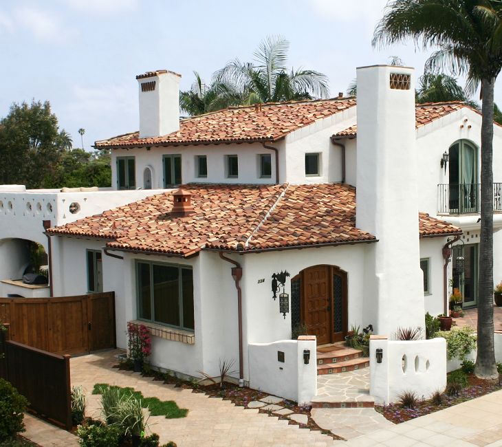 a large white house with red tile roofing and palm trees in the front yard