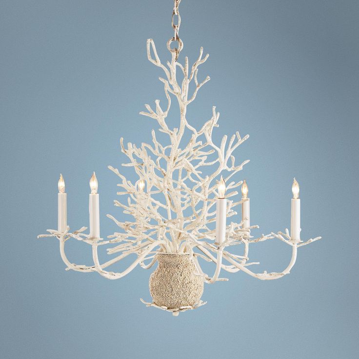 a white chandelier hanging from a ceiling in a room with light blue walls