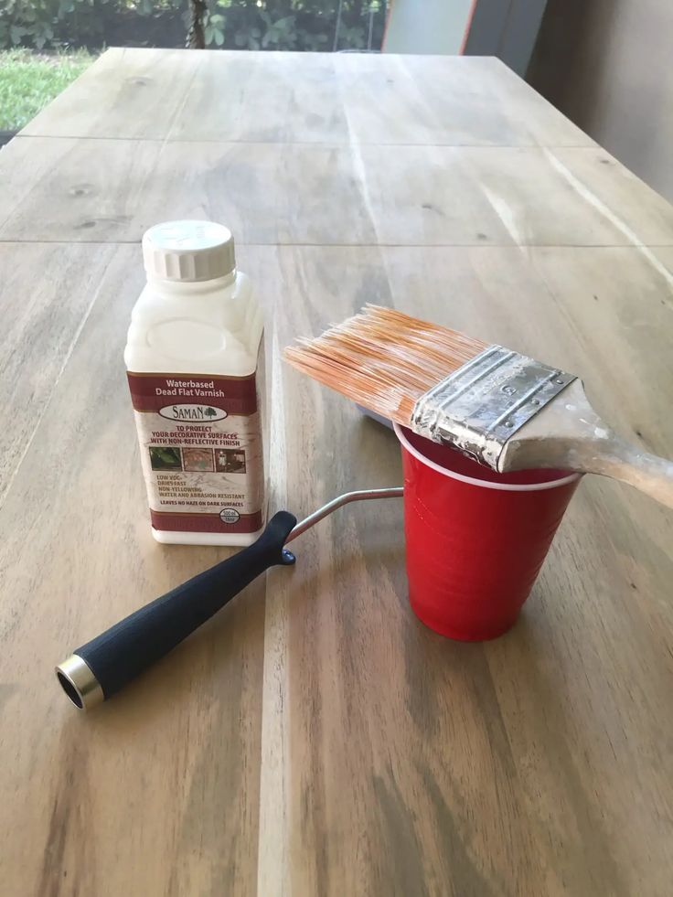 a wooden table with paint and a brush next to it on top of the table