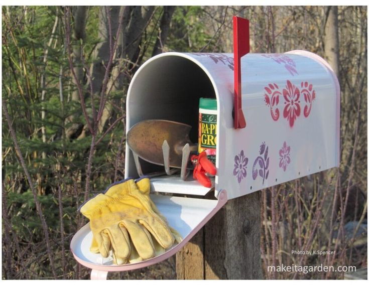 a mailbox with gloves and other items on it in front of some trees,