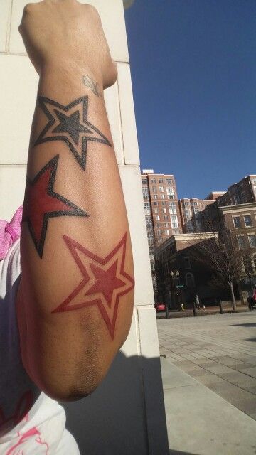 a man with tattoos on his arm and hand next to a brick wall in the city