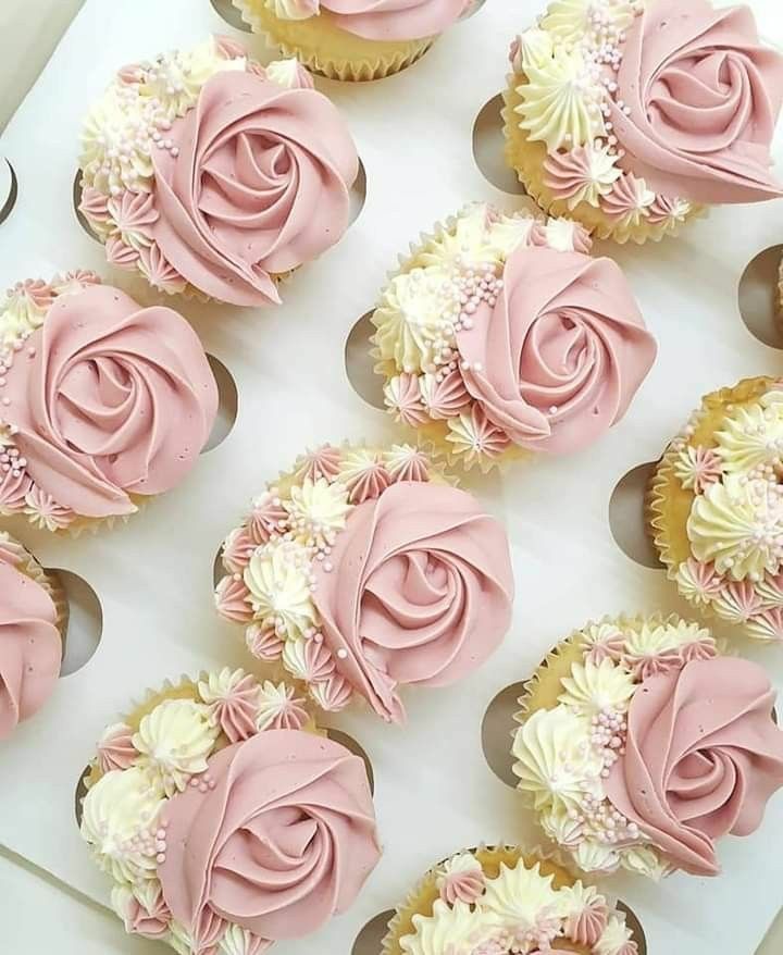 several cupcakes with pink frosting and white flowers on the top are arranged in a box