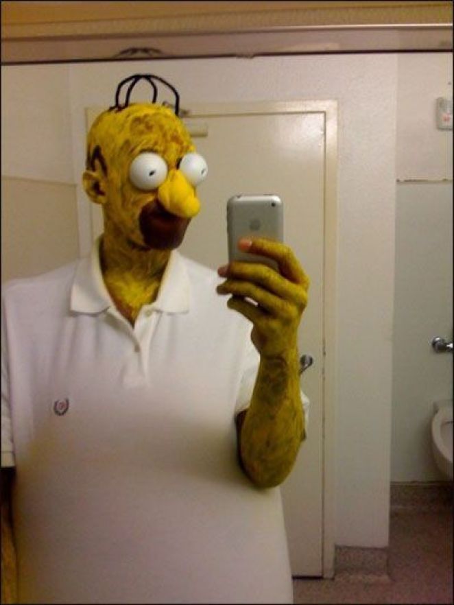 a man dressed as the simpsons taking a selfie with his cell phone in front of him