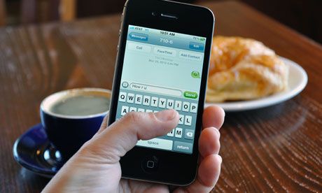 a person holding an iphone in front of a cup of coffee and croissants