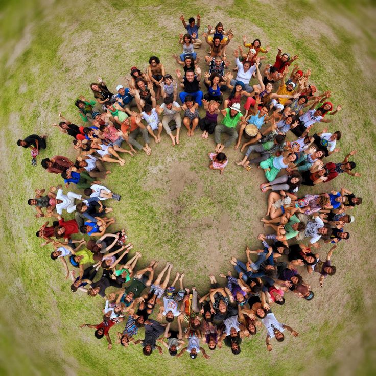 a group of people standing in the shape of a circle on top of a grass covered field