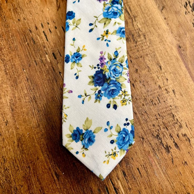 Beautiful floral tie in a bright white and blue. This 100% cotton tie would look so lovely at a spring or summer wedding, either for the groom, groomsmen, ushers or wedding guests. The fabric is soft to the touch and the colours look amazing together. Material: 100% viscose Size: 145cm x 6cm This item will be hand gift wrapped before posting. Summer Formal Cotton Suit Accessories, Formal Cotton Suit And Tie Accessories For Summer, Cotton Ties For Black Tie Events In Summer, Cotton Ties For Black Tie Occasions In Summer, White Cotton Ties For Formal Occasions, Elegant Blue Cotton Suit And Tie Accessories, Cotton Standard Tie Perfect For Gifts, Cotton Standard Tie Suitable For Gifts, Cotton Standard Tie As Gift