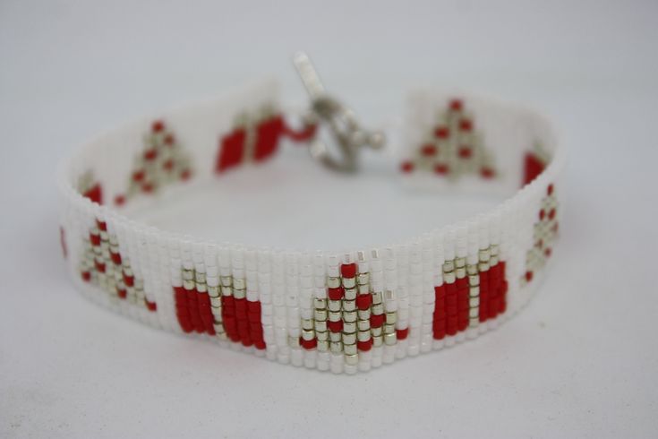 a red and white beaded bracelet with christmas trees on the front, in rows of squares