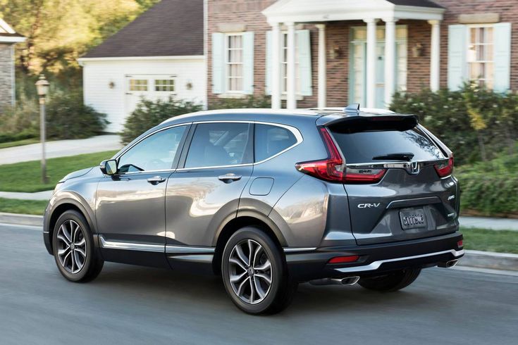 the rear end of a silver honda cr - v driving down a street with houses in the background