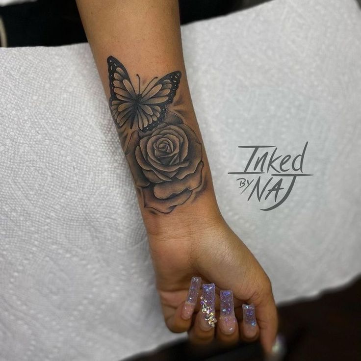 a woman's arm with a butterfly and rose tattoo on the left side of her wrist