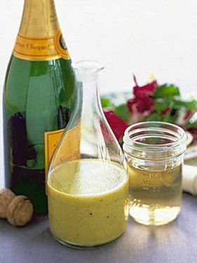 a bottle of wine next to a bowl of salad and a glass with dressing in it