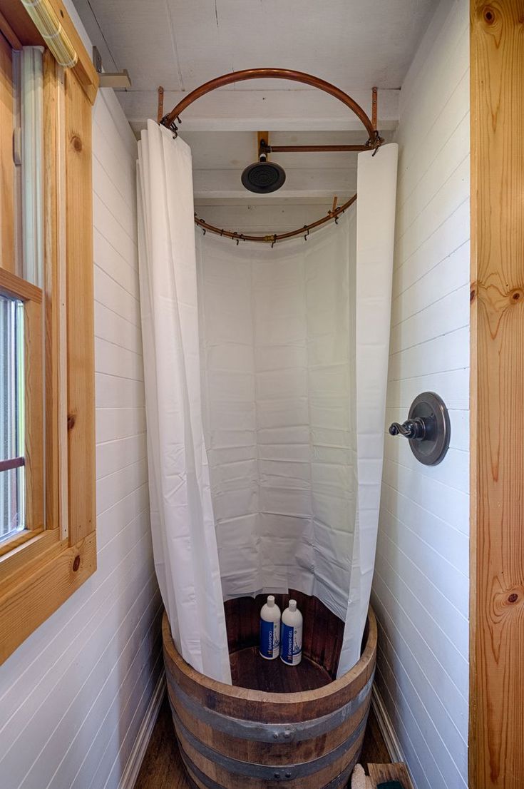 a bathroom with a wooden barrel in the corner and two bottles on the floor next to it