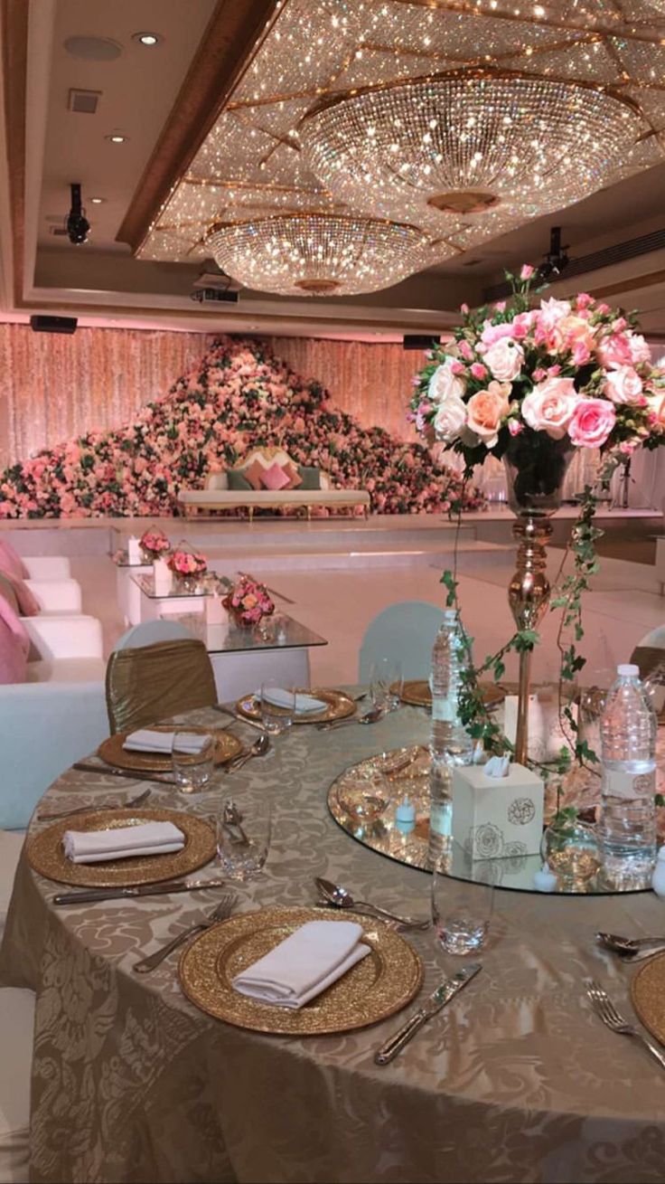 a table set up for a formal function with flowers and candles on the centerpieces