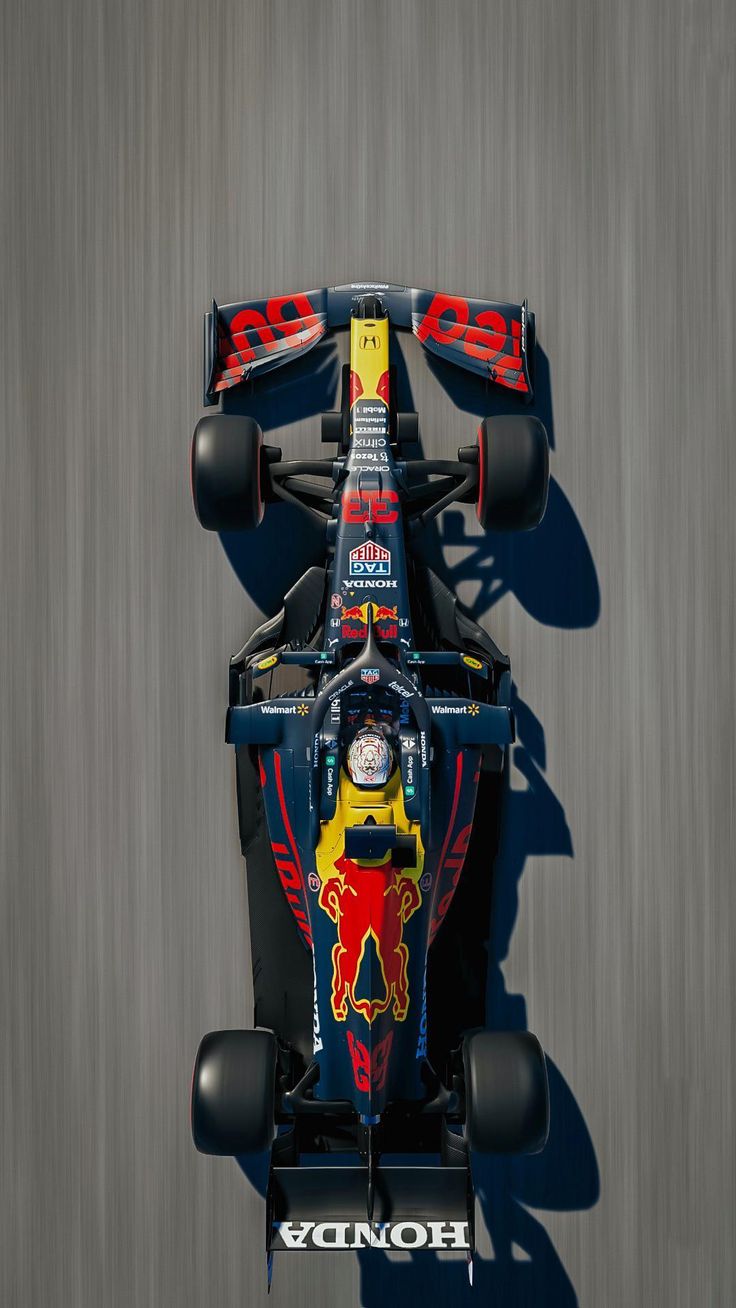 a red bull racing car driving down the road with its front wheels in motion, viewed from above