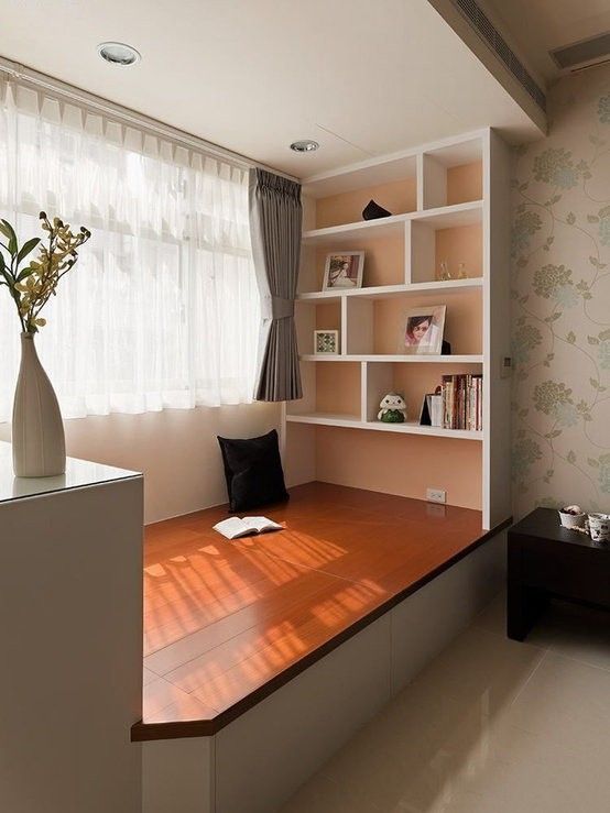 a room with a desk, shelves and flowers on the table in front of it