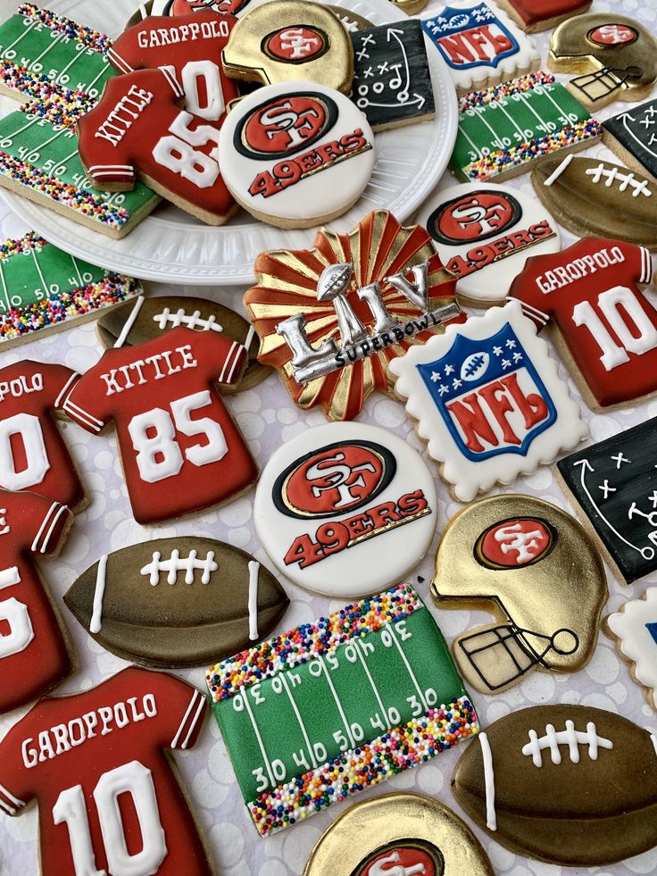 decorated cookies are arranged in the shape of footballs and numbers on paper plates with confetti sprinkles