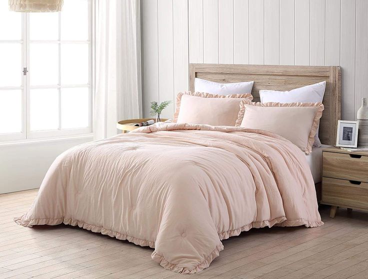 a bed with pink comforter and pillows in a room