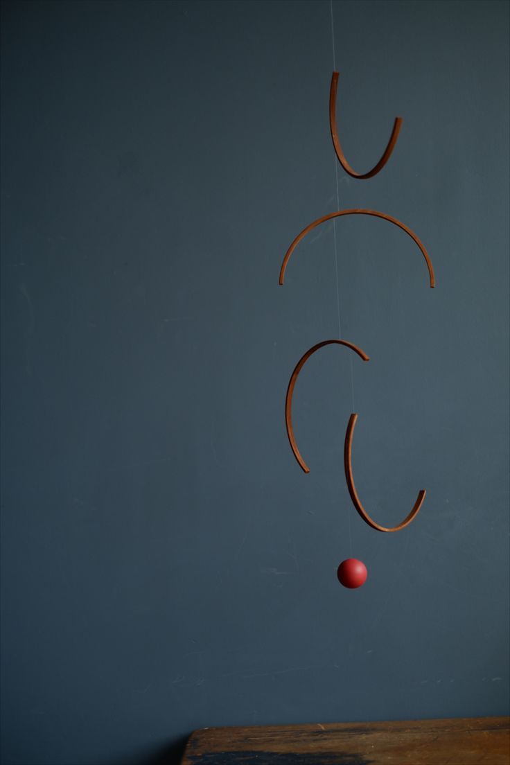 a wooden mobile hanging from the ceiling with a red ball in it's mouth