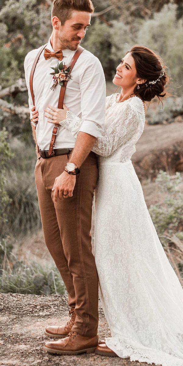 a bride and groom standing together in the woods